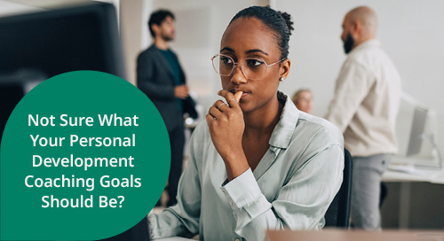 A woman with glasses sits thoughtfully at a desk, looking pensive, as two colleagues discuss in the background. The text overlay reads, 'Not Sure What Your Personal Development Coaching Goals Should Be?'