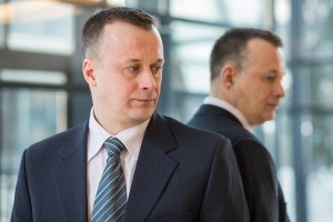 A businessman in a suit and tie stands near a mirror