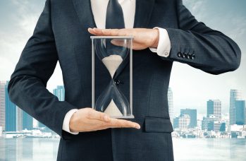 Businessman Holding Hourglass At Megapolis City Background, Time